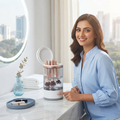 South Asian woman cleaning makeup brushes with an electric device on a modern vanity.